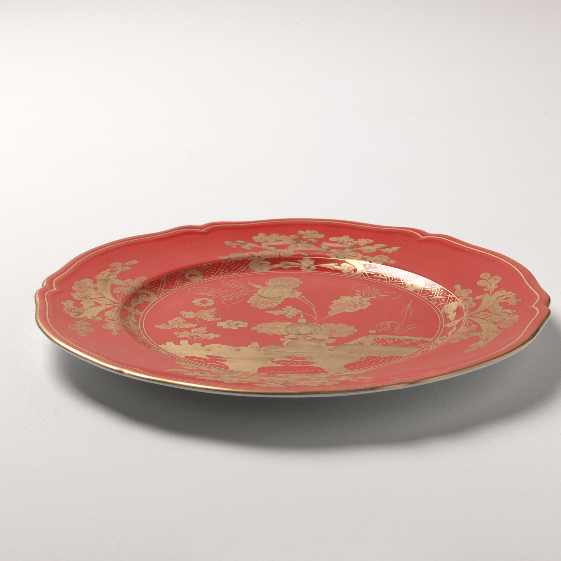 Elevate your dining experience with the exquisite Oriente Italiano Collection Porcelain RUBRUM Charger Plate, a masterpiece from Ginori 1735. This luxurious charger plate is meticulously crafted from fine white porcelain, offering a canvas for intricate artistry. The delicate floral ornamentation, hand-painted in pure gold, traces the classic lines of the Antico Doccia pattern, a signature of the esteemed Florentine Maison.