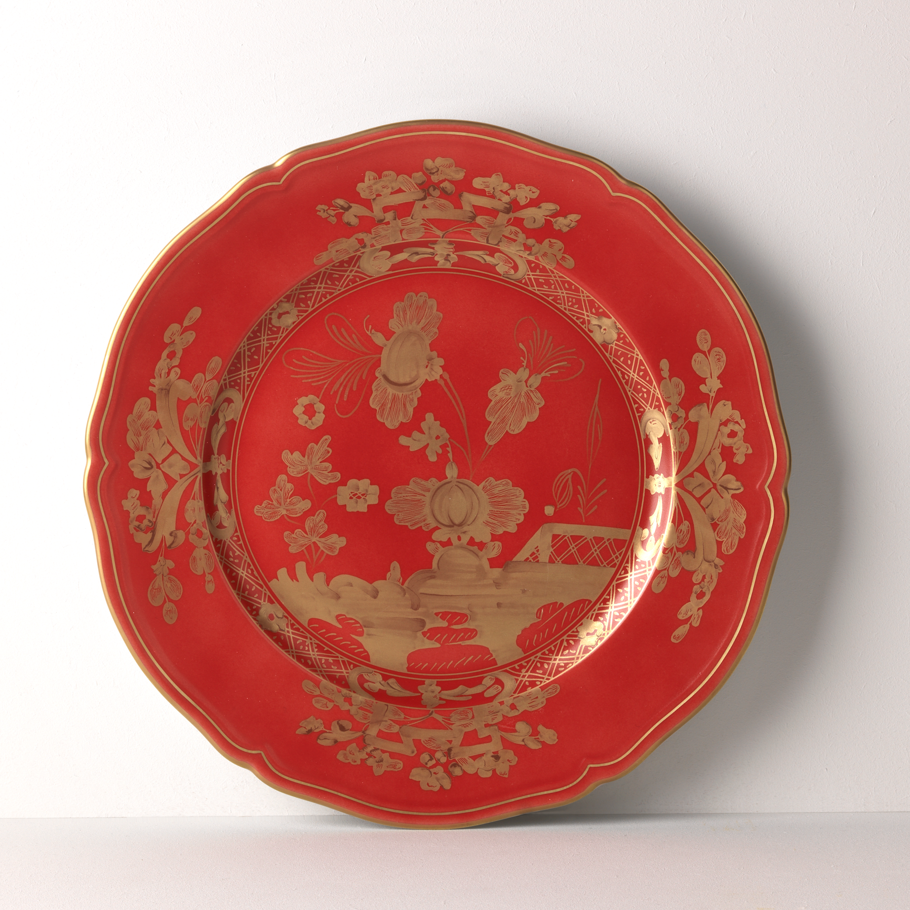 Elevate your dining experience with the exquisite Oriente Italiano Collection Porcelain RUBRUM Charger Plate, a masterpiece from Ginori 1735. This luxurious charger plate is meticulously crafted from fine white porcelain, offering a canvas for intricate artistry. The delicate floral ornamentation, hand-painted in pure gold, traces the classic lines of the Antico Doccia pattern, a signature of the esteemed Florentine Maison.