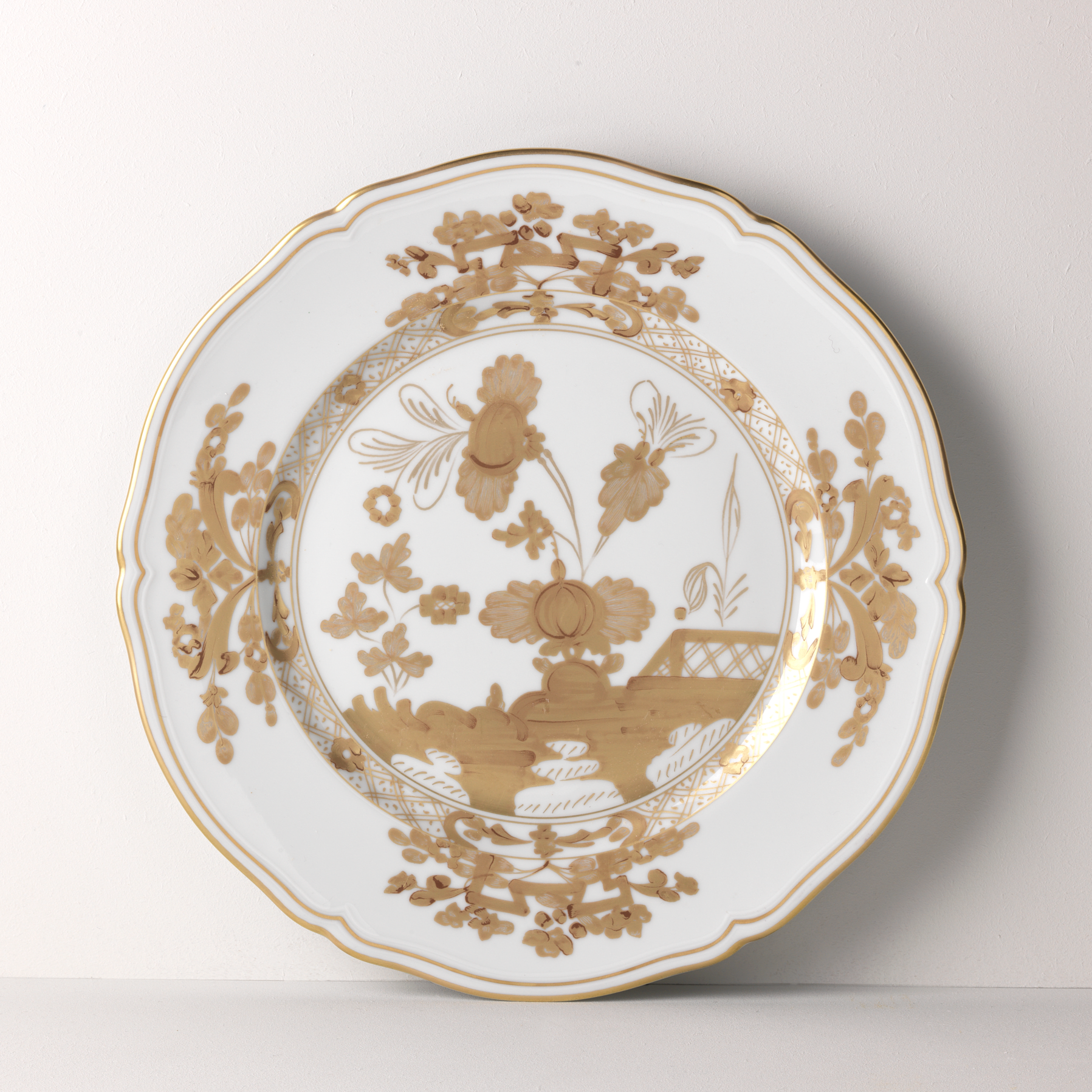 Elevate your dining experience with the exquisite Oriente Italiano Collection Porcelain AURUM Charger Plate, a masterpiece from Ginori 1735. This luxurious charger plate is meticulously crafted from fine white porcelain, offering a canvas for intricate artistry. The delicate floral ornamentation, hand-painted in pure gold, traces the classic lines of the Antico Doccia pattern, a signature of the esteemed Florentine Maison.