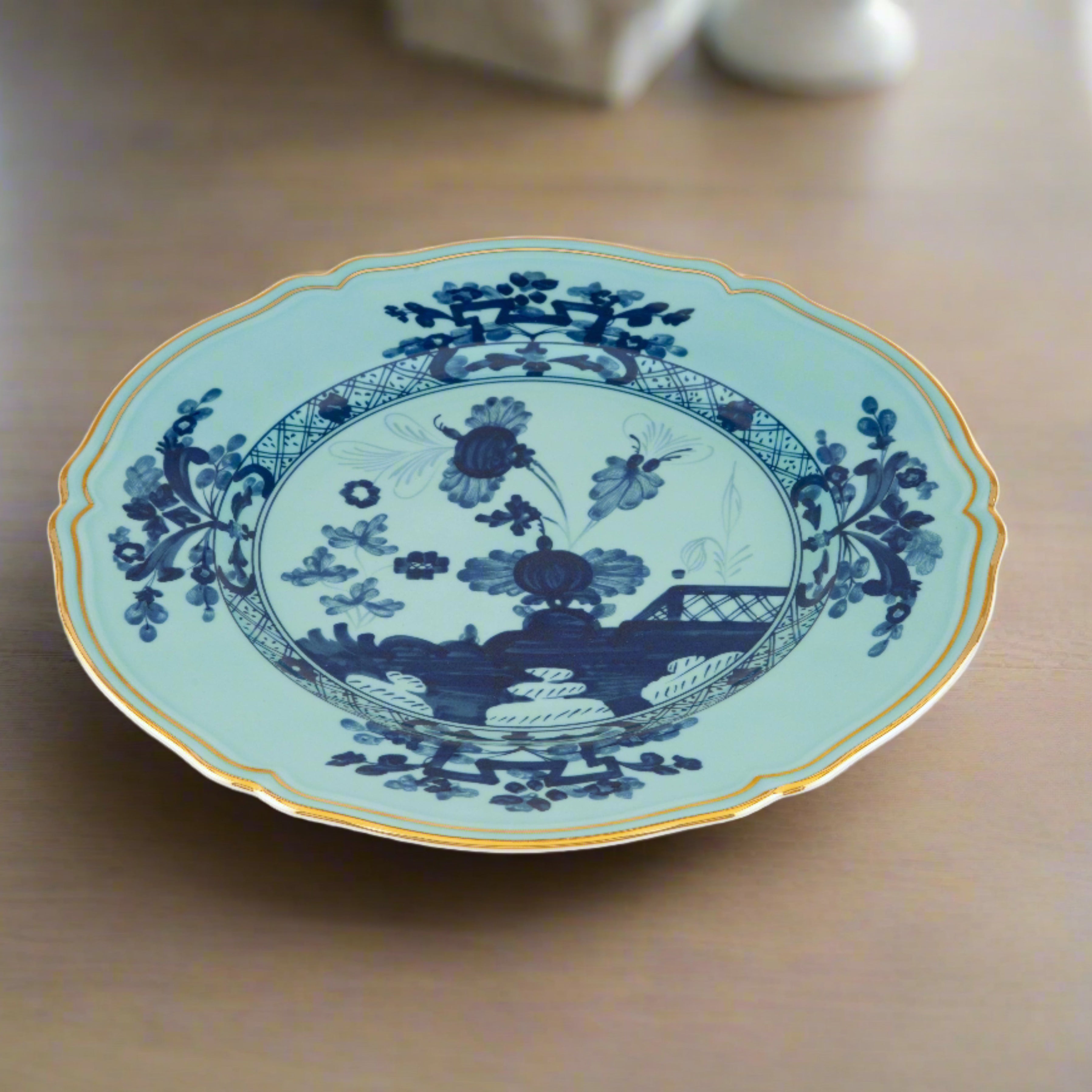 Elevate your dining experience with the exquisite Oriente Italiano Collection Porcelain Charger Plate, a masterpiece from Ginori 1735. This luxurious charger plate is meticulously crafted from fine white porcelain, offering a canvas for intricate artistry. The delicate floral ornamentation, hand-painted in pure gold, traces the classic lines of the Antico Doccia pattern, a signature of the esteemed Florentine Maison.