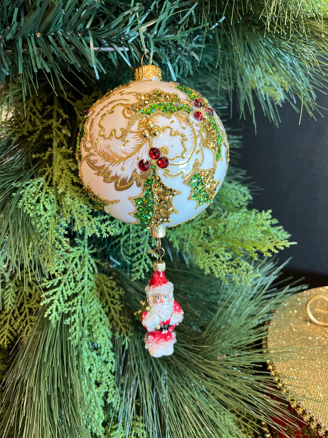 This exquisite ornament features Santa dropping from a gorgeous ball decorated with holly and gold leaves encrusted with chunky glitter and rhinestones.
