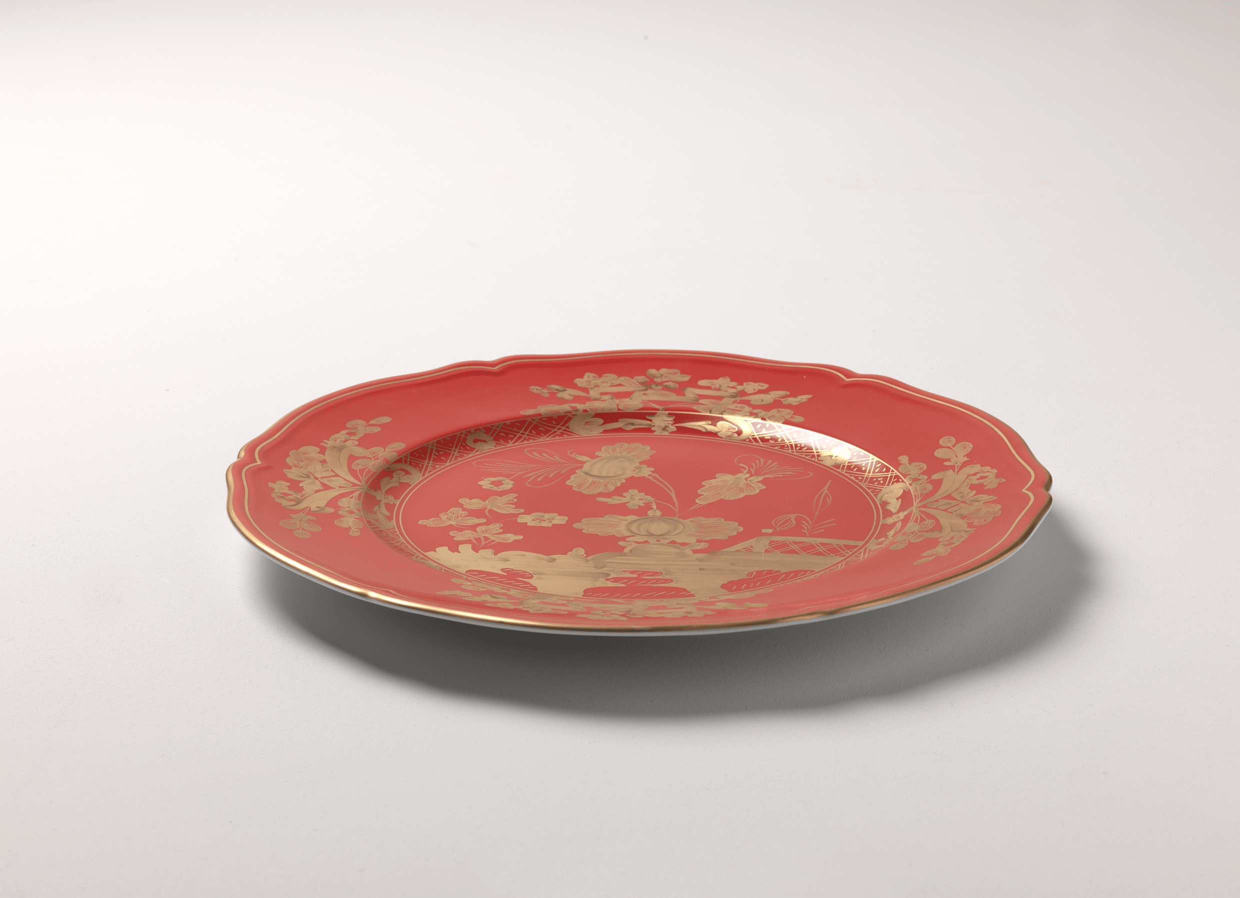 Elevate your dining experience with the exquisite Oriente Italiano Collection Porcelain  RUBRUM Charger Plate, a masterpiece from Ginori 1735. This luxurious charger plate is meticulously crafted from fine white porcelain, offering a canvas for intricate artistry. The delicate floral ornamentation, hand-painted in pure gold, traces the classic lines of the Antico Doccia pattern, a signature of the esteemed Florentine Maison.
