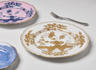 Elevate your dining experience with the exquisite Oriente Italiano Collection Porcelain  AURUM Charger Plate, a masterpiece from Ginori 1735. This luxurious charger plate is meticulously crafted from fine white porcelain, offering a canvas for intricate artistry. The delicate floral ornamentation, hand-painted in pure gold, traces the classic lines of the Antico Doccia pattern, a signature of the esteemed Florentine Maison.