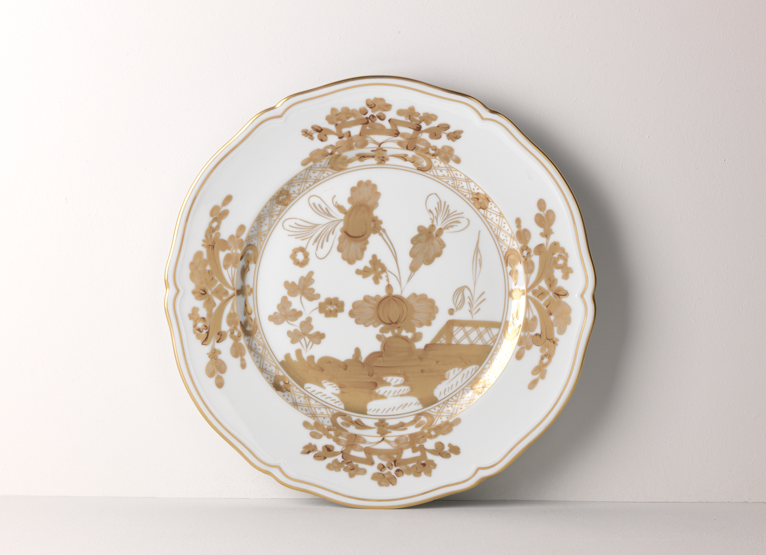 Elevate your dining experience with the exquisite Oriente Italiano Collection Porcelain  AURUM Charger Plate, a masterpiece from Ginori 1735. This luxurious charger plate is meticulously crafted from fine white porcelain, offering a canvas for intricate artistry. The delicate floral ornamentation, hand-painted in pure gold, traces the classic lines of the Antico Doccia pattern, a signature of the esteemed Florentine Maison.