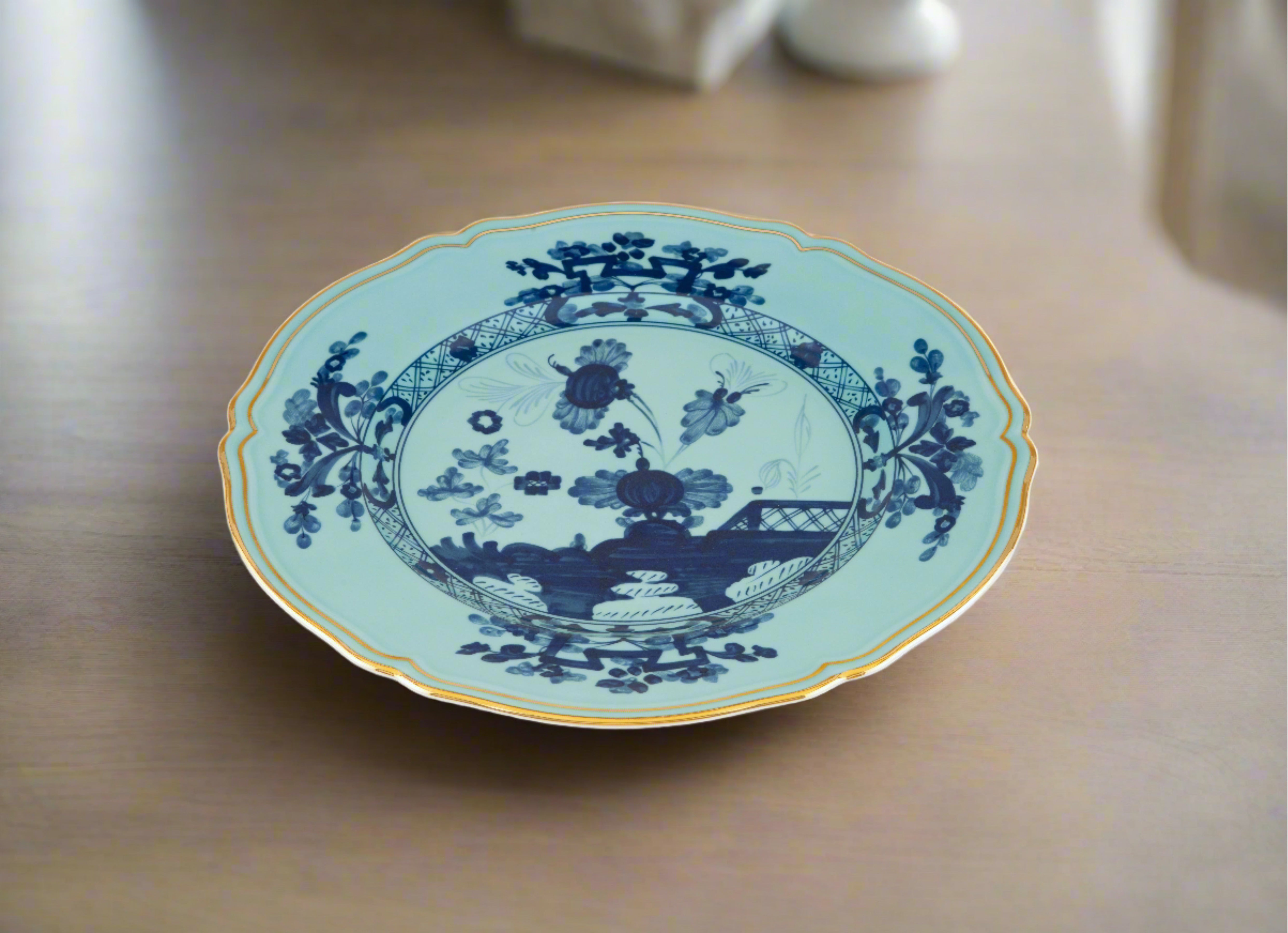 Elevate your dining experience with the exquisite Oriente Italiano Collection Porcelain Charger Plate, a masterpiece from Ginori 1735. This luxurious charger plate is meticulously crafted from fine white porcelain, offering a canvas for intricate artistry. The delicate floral ornamentation, hand-painted in pure gold, traces the classic lines of the Antico Doccia pattern, a signature of the esteemed Florentine Maison.