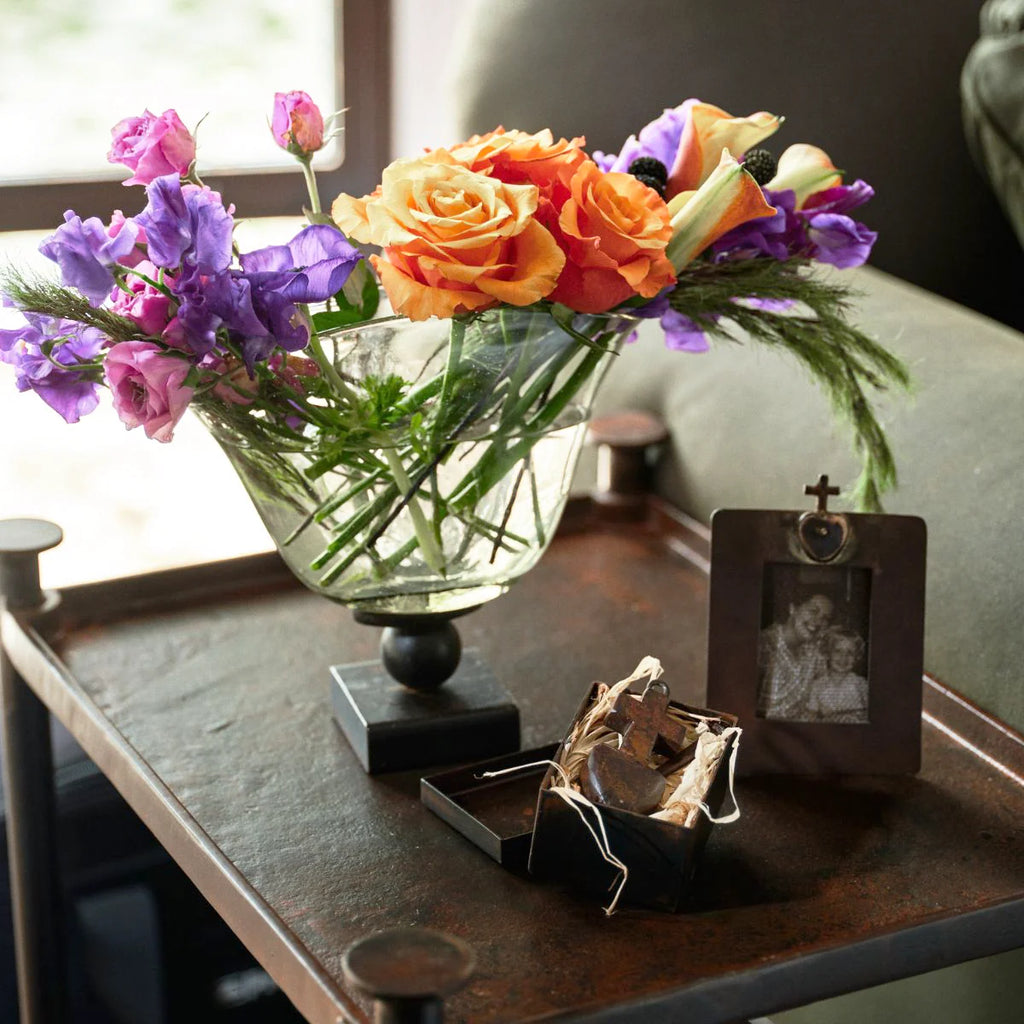 Fan-shaped vase resting atop a balin stand . . . each one uniqe, celebrates the mouth blown differences . . . candles, flowers . . .