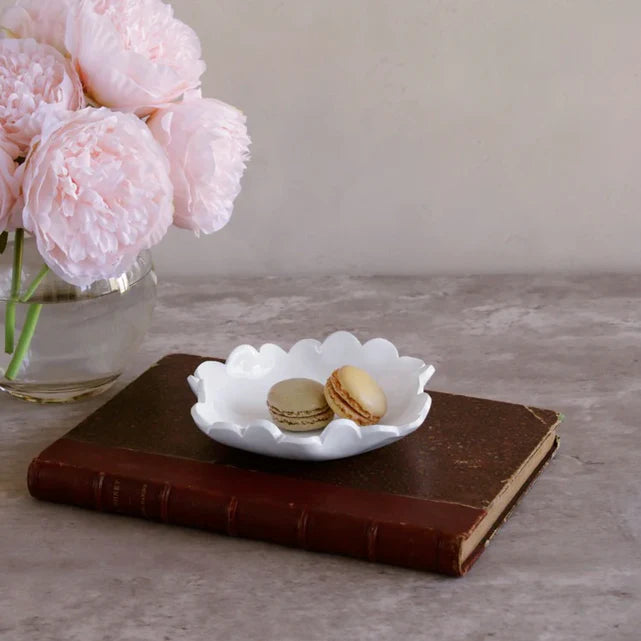 White dish containing macarons and pink flowers in the background