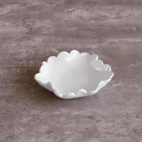 White ceramic dish with scalloped edge on a gray surface