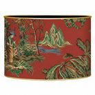 A cylindrical lampshade featuring a red background with a classic Chinese landscape print in green, gold, and brown, 