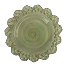 Decorative ceramic plate with scalloped edge and swirling center design on a black background